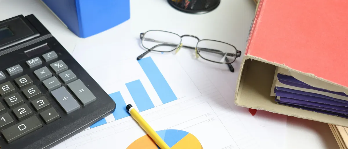 A calculator and financial documents laid out on a desk