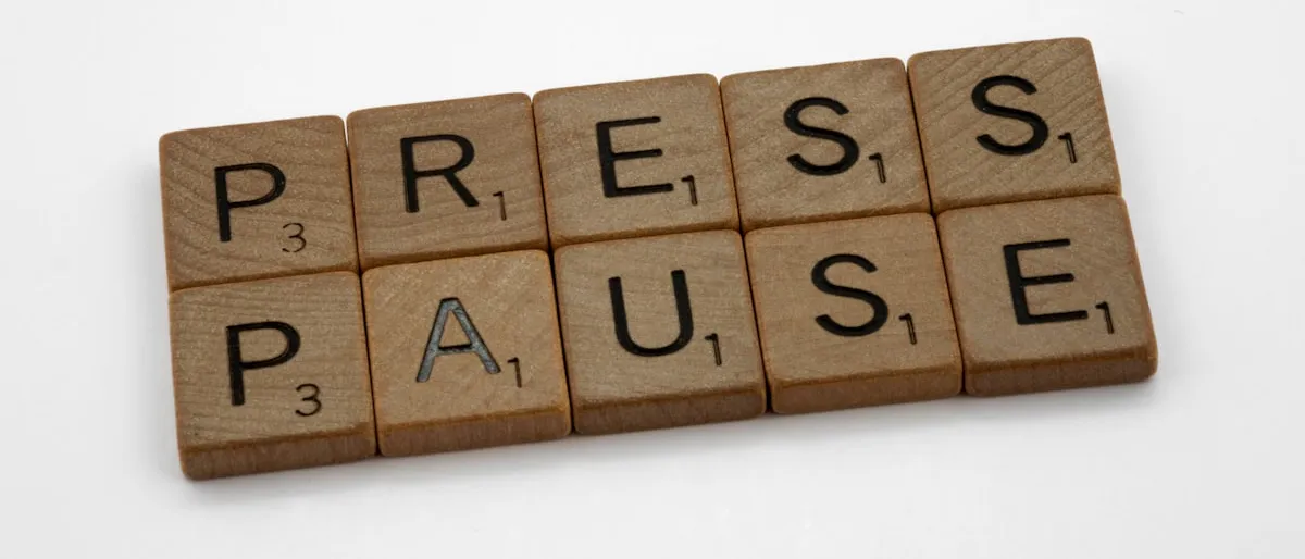 Wooden scrabble tiles spelling out 'press pause'