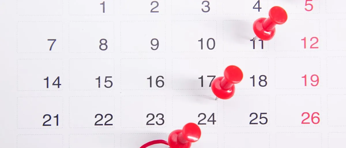 A wall calendar with red push pins marking dates leading up to the 30th