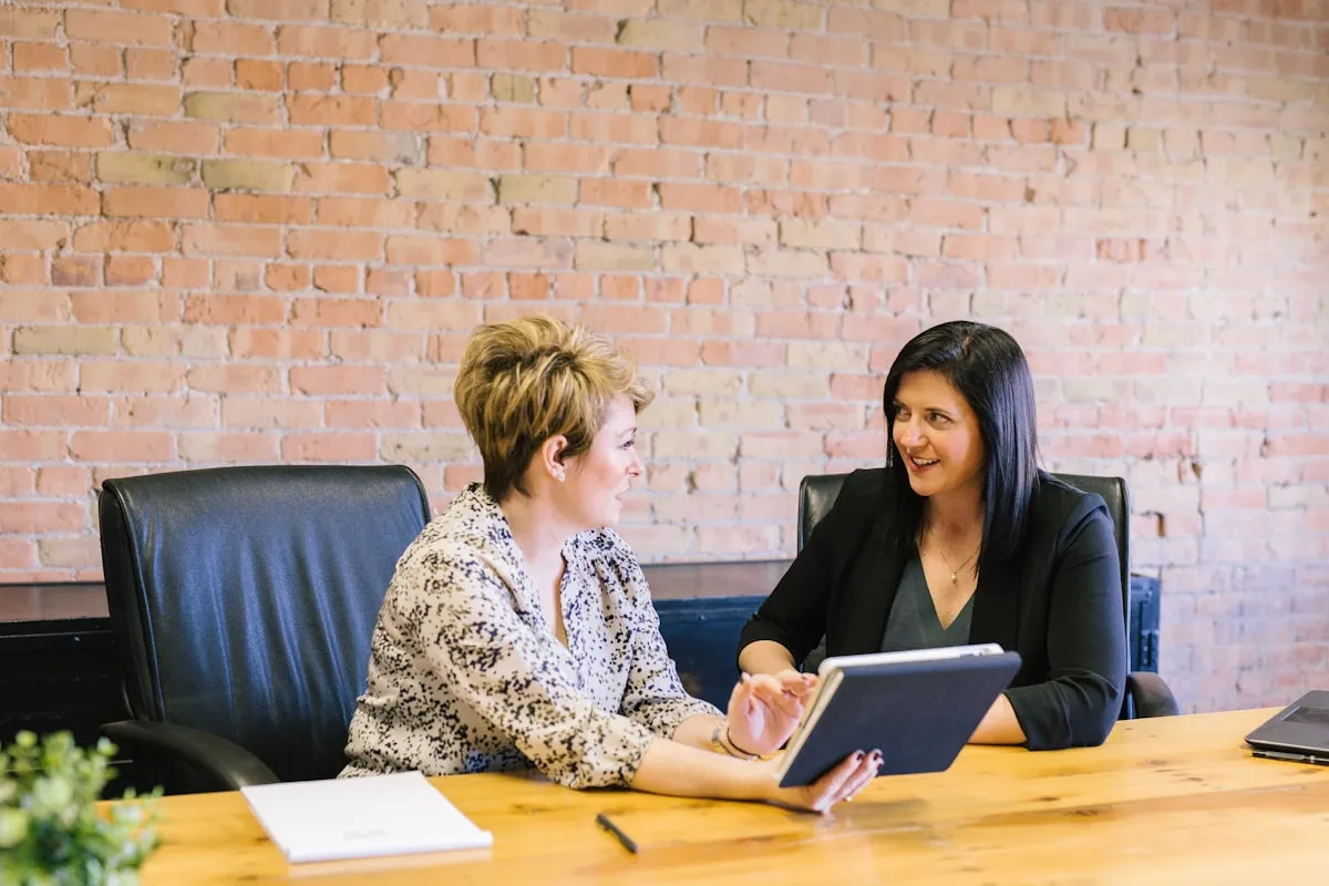 Two women in a business meeting reviewing a tablet together
