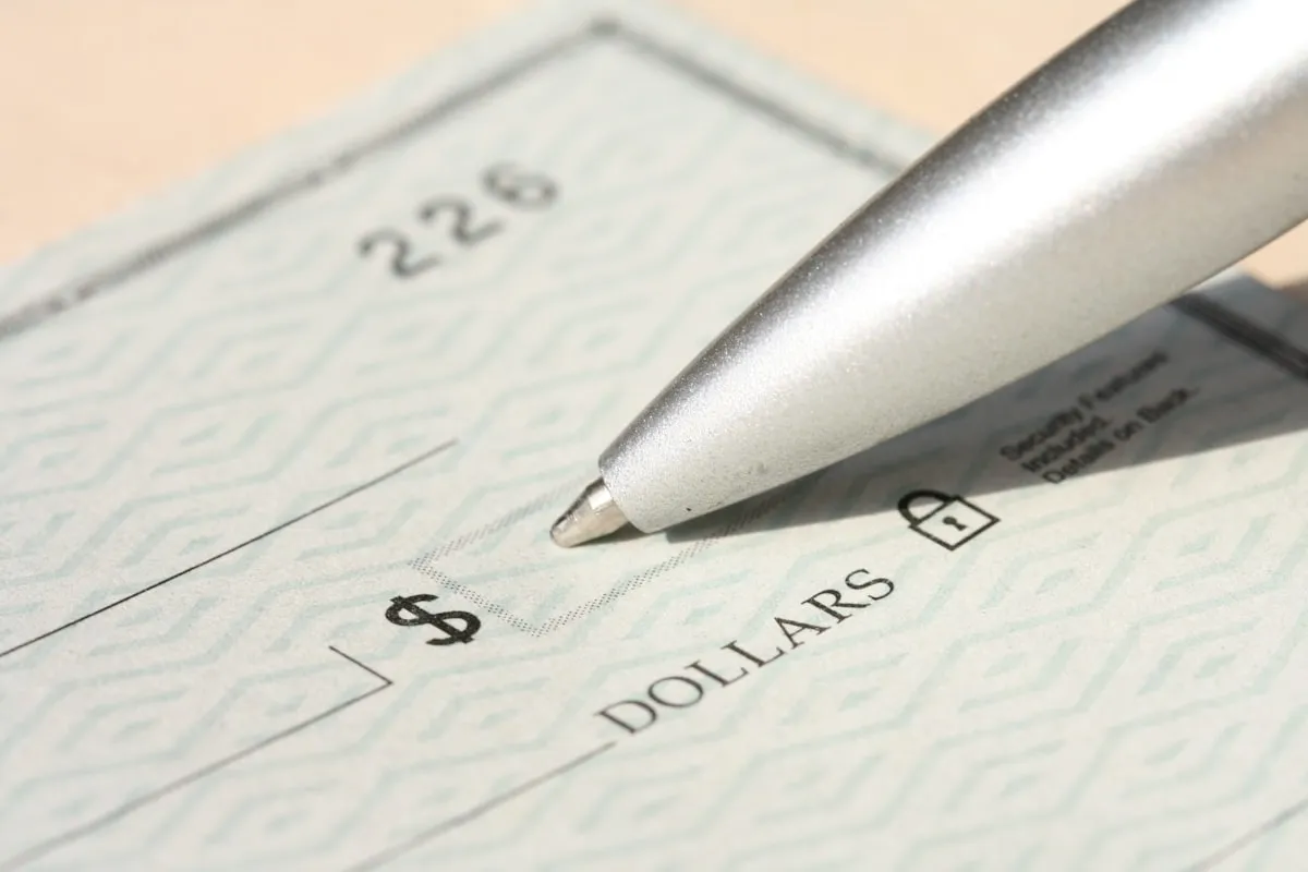 A pen resting on a signed paycheck