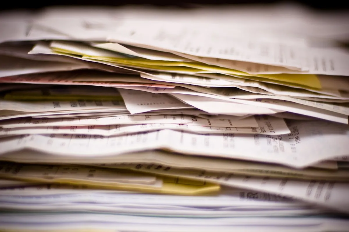 A thick stack of overlapping paper statements and receipts