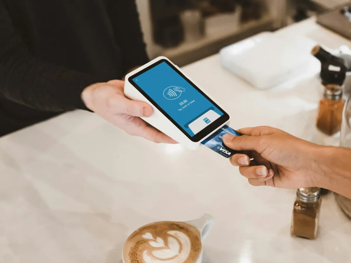 A customer paying with a card at a point-of-sale terminal in a cafe